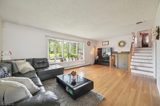 living room featuring a textured ceiling, wood-type flooring, and baseboard heating