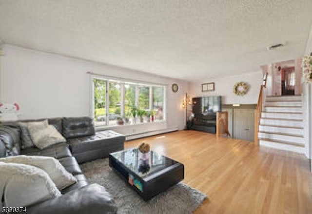 living room featuring a textured ceiling, hardwood / wood-style flooring, and a baseboard heating unit