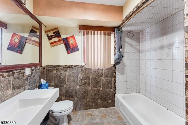 bathroom with toilet, tile walls, and tiled shower / bath