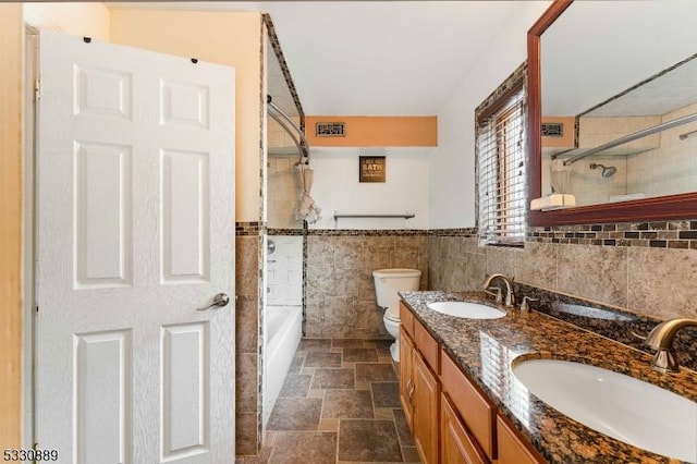 full bathroom with vanity, toilet, tile walls, and tiled shower / bath