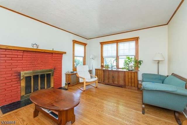 sitting room featuring a fireplace, a textured ceiling, light hardwood / wood-style floors, and crown molding