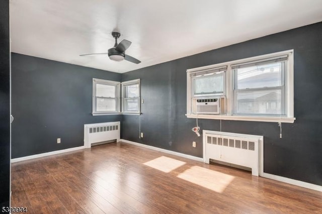 spare room featuring ceiling fan, radiator heating unit, cooling unit, and hardwood / wood-style flooring