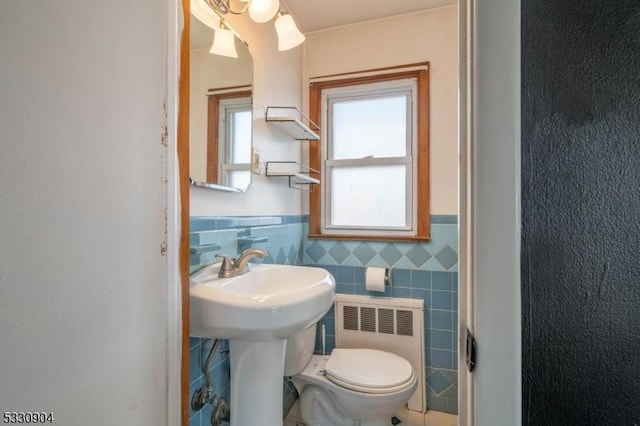 bathroom featuring sink, toilet, radiator, and tile walls