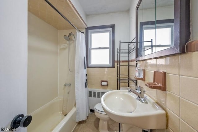 full bathroom with radiator heating unit, shower / tub combo, tile walls, and a healthy amount of sunlight