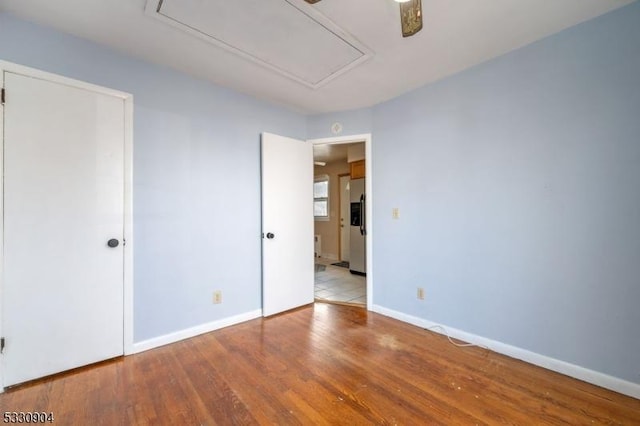 unfurnished bedroom featuring white fridge with ice dispenser and light hardwood / wood-style floors