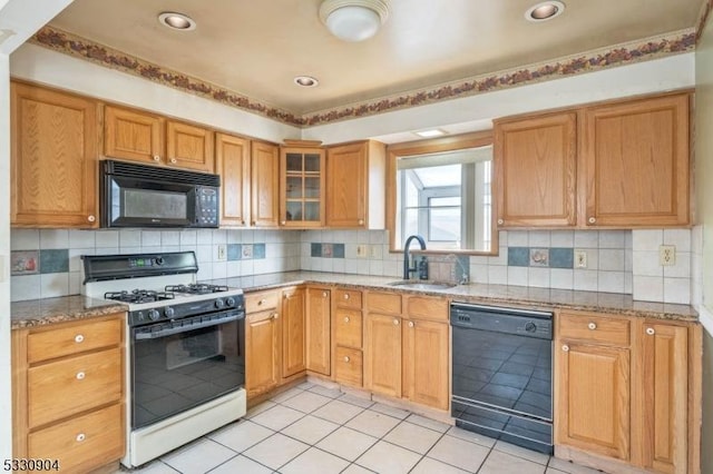 kitchen featuring sink, light stone counters, backsplash, light tile patterned floors, and black appliances