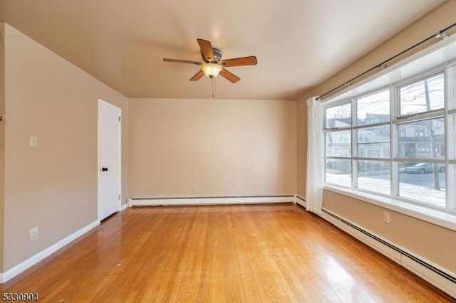 spare room featuring light hardwood / wood-style flooring, ceiling fan, and a baseboard heating unit