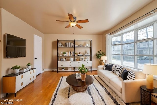 living room with light wood-type flooring, a baseboard radiator, and ceiling fan