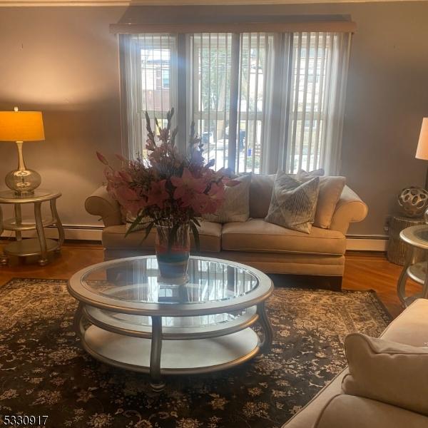 living room with hardwood / wood-style flooring and a baseboard heating unit