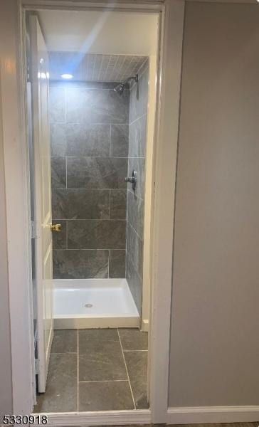 bathroom with a tile shower and tile patterned flooring