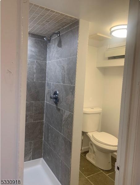 bathroom featuring tiled shower, tile patterned floors, and toilet