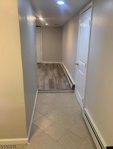 hallway with light tile patterned floors and a baseboard radiator