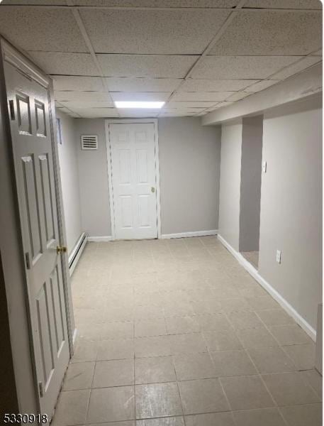 basement featuring a paneled ceiling and a baseboard radiator