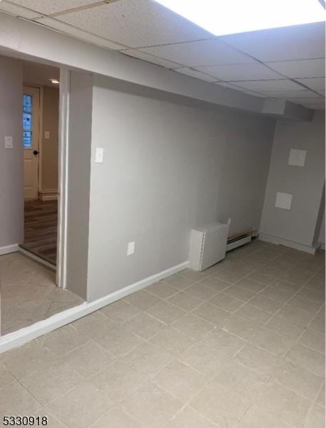 basement featuring a baseboard heating unit and a paneled ceiling