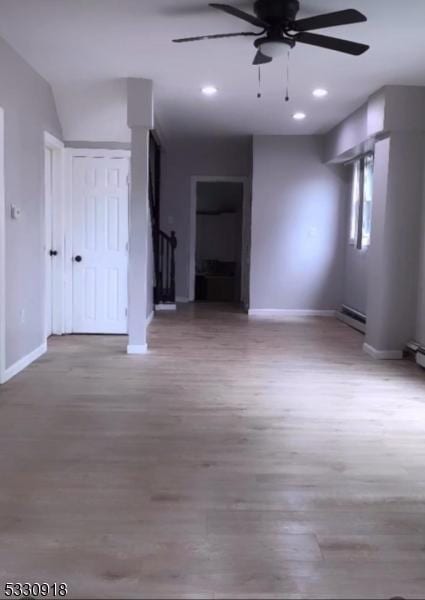 unfurnished room with ceiling fan, wood-type flooring, and a baseboard heating unit