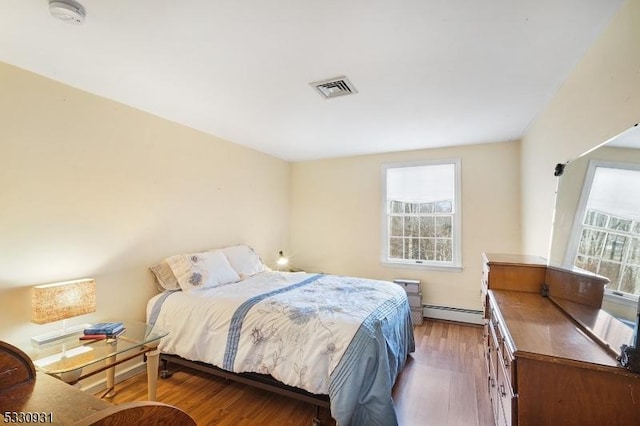 bedroom featuring baseboard heating and hardwood / wood-style flooring