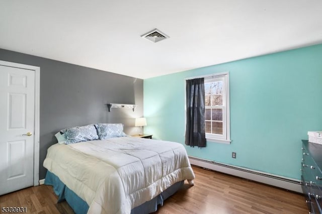 bedroom featuring baseboard heating and wood-type flooring