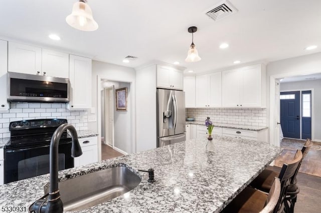 kitchen with light stone countertops, stainless steel appliances, sink, pendant lighting, and white cabinetry