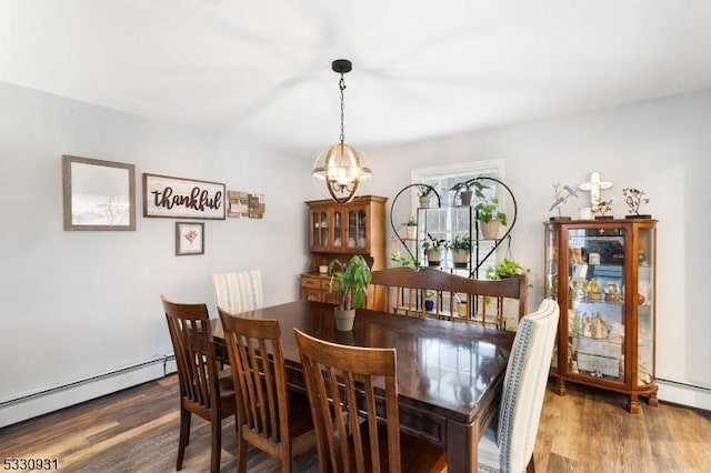 dining room with hardwood / wood-style floors, a baseboard radiator, and a notable chandelier