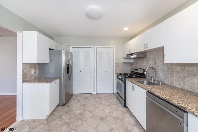 kitchen with white cabinetry, stainless steel appliances, backsplash, stone counters, and sink