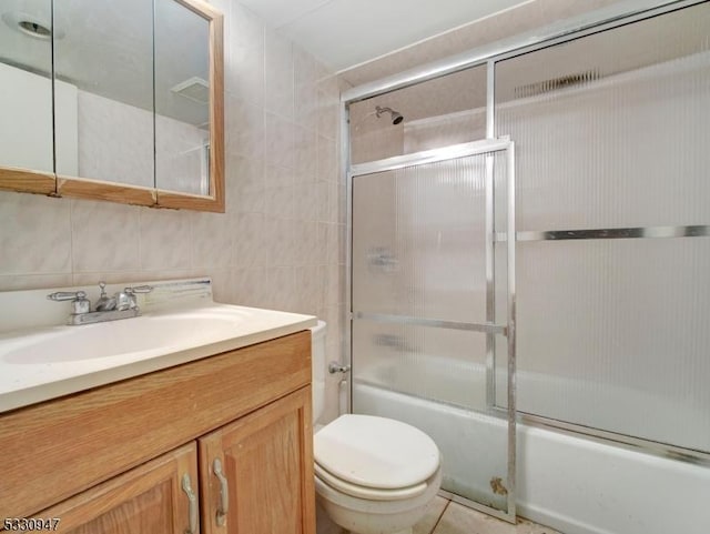 full bathroom with vanity, toilet, enclosed tub / shower combo, tile walls, and tasteful backsplash