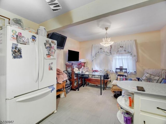 kitchen with pendant lighting, white fridge, and a notable chandelier