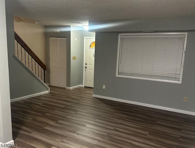 empty room featuring a textured ceiling and dark wood-type flooring