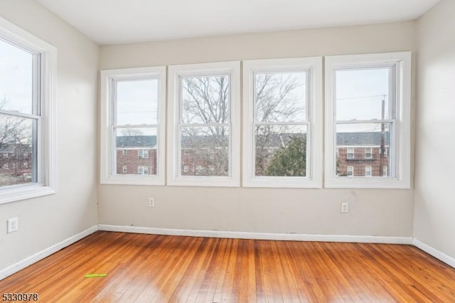 empty room with wood-type flooring and a healthy amount of sunlight