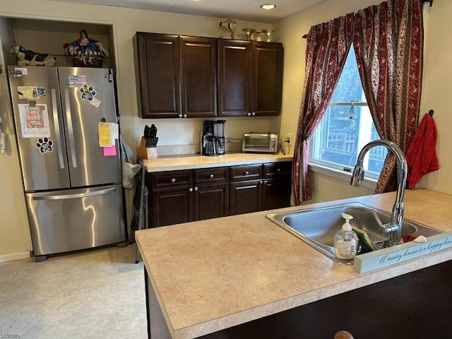 kitchen featuring dark brown cabinets, stainless steel fridge, and sink