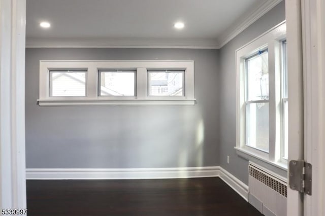 empty room featuring wood-type flooring, radiator, and crown molding