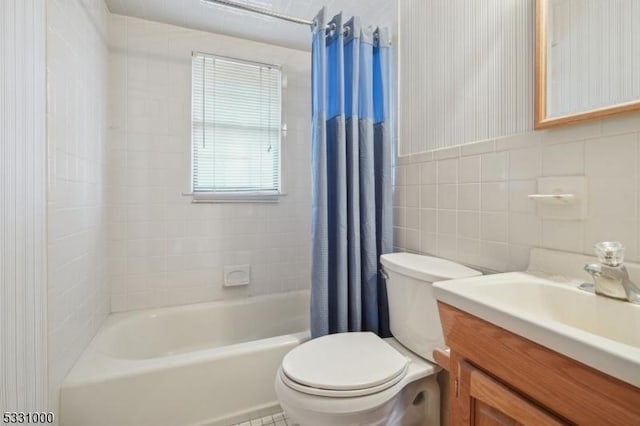 full bathroom with toilet, shower / tub combo, vanity, and tile walls