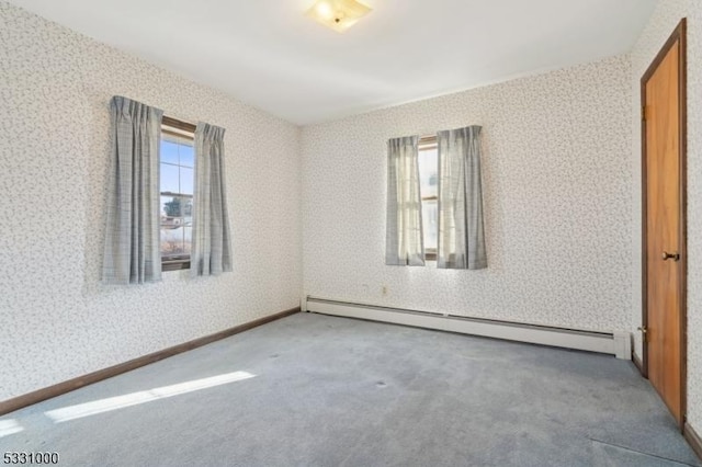 carpeted empty room featuring a healthy amount of sunlight and a baseboard heating unit