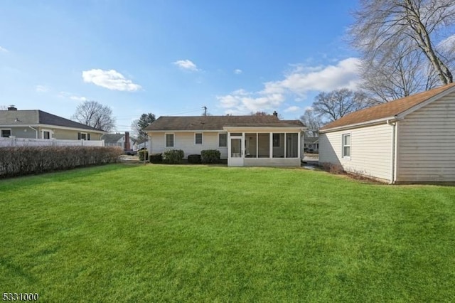 rear view of house featuring a lawn and a sunroom