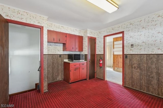 kitchen featuring baseboard heating, ornamental molding, and dark colored carpet