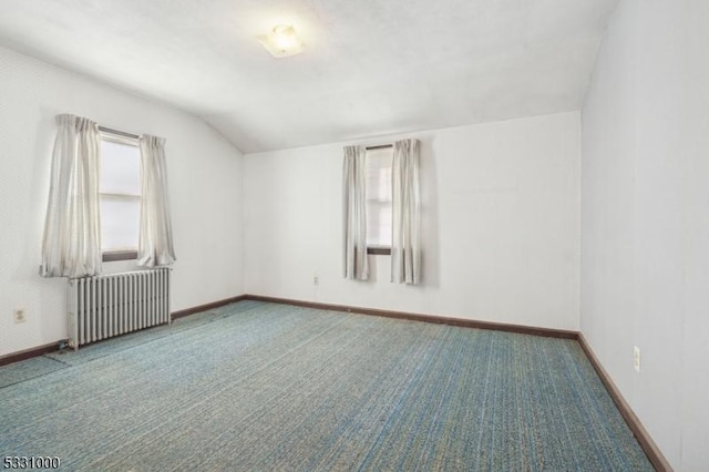 carpeted empty room with vaulted ceiling and radiator