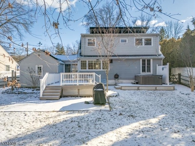 snow covered property featuring a hot tub and a wooden deck