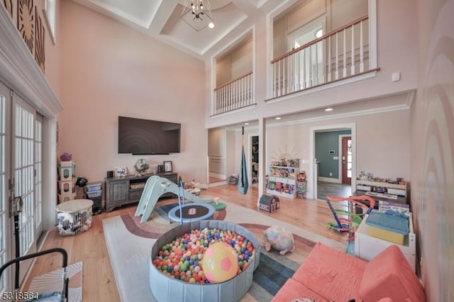 interior space featuring coffered ceiling, a high ceiling, beamed ceiling, a chandelier, and wood-type flooring