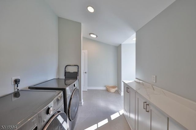 laundry room with washer and clothes dryer, light tile patterned floors, and cabinets