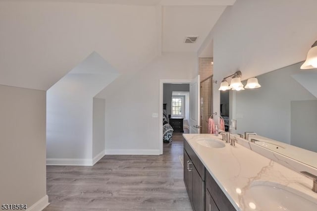 bathroom featuring vanity, wood-type flooring, and vaulted ceiling