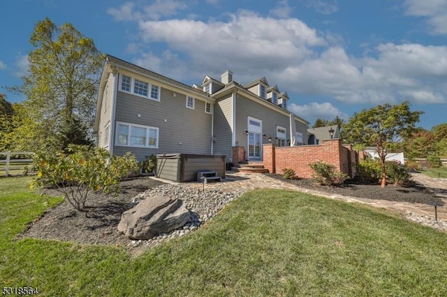 rear view of house featuring a yard and a hot tub