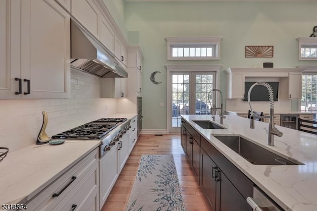 kitchen with dark brown cabinets, white cabinetry, light stone countertops, and sink