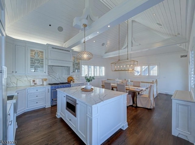 kitchen featuring a center island, decorative backsplash, hanging light fixtures, appliances with stainless steel finishes, and white cabinets