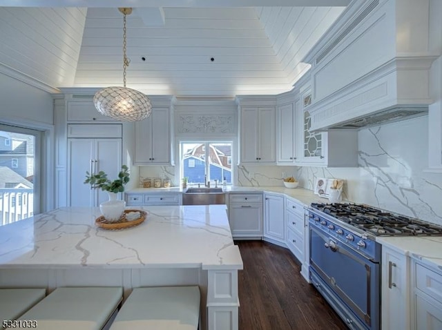 kitchen with white cabinetry, pendant lighting, range, and light stone counters