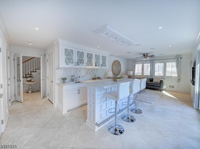 kitchen with a kitchen island, crown molding, a kitchen bar, and white cabinets