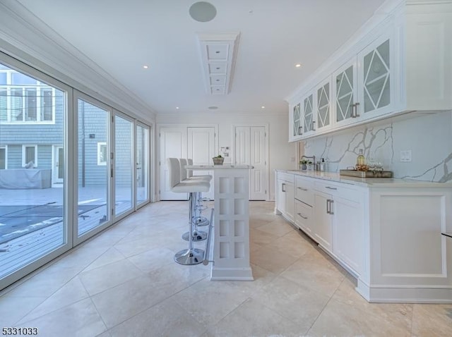 kitchen featuring a kitchen bar, white cabinetry, ornamental molding, and a kitchen island