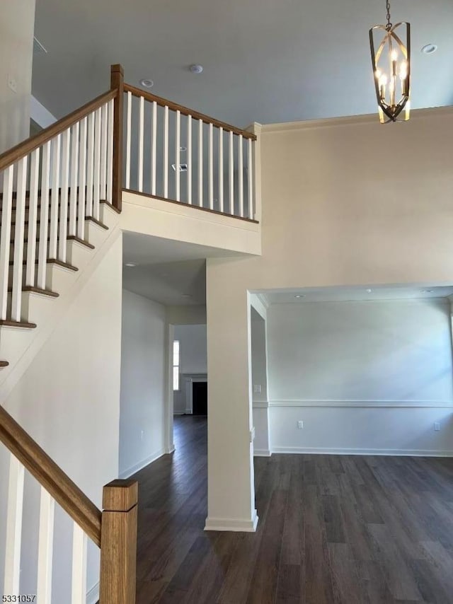 stairs with hardwood / wood-style floors and an inviting chandelier