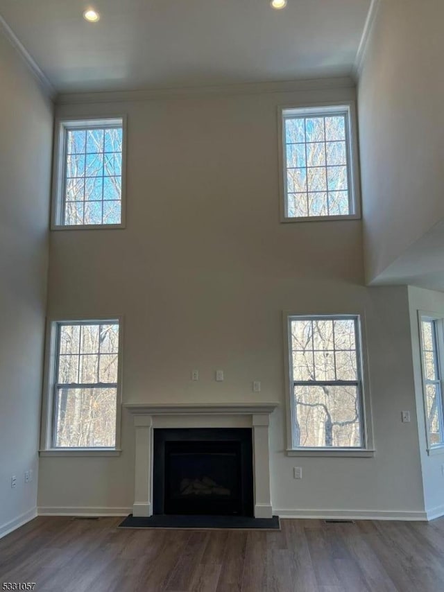 unfurnished living room with dark hardwood / wood-style floors, crown molding, and a high ceiling