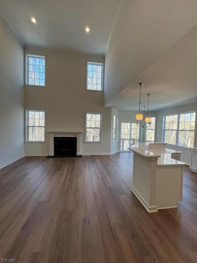 unfurnished living room with dark hardwood / wood-style floors and a towering ceiling