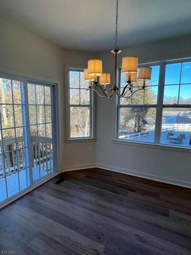 unfurnished dining area with dark wood-type flooring and a chandelier