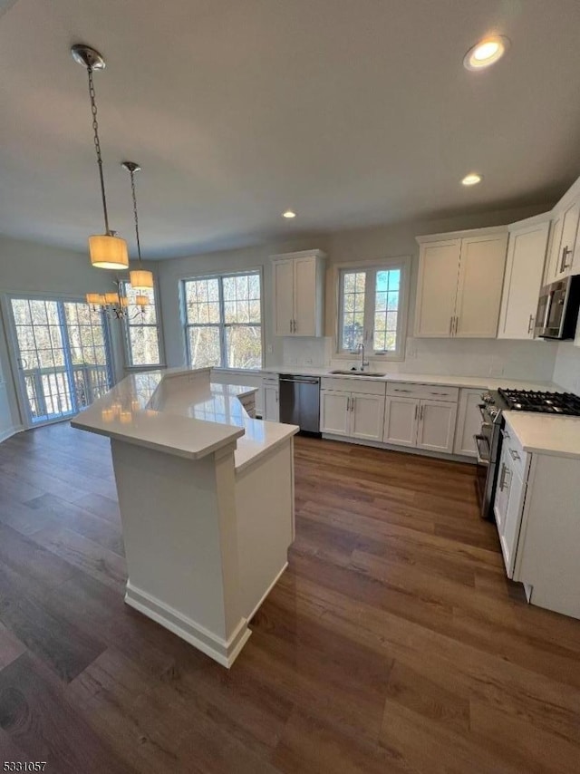 kitchen featuring white cabinets, pendant lighting, stainless steel appliances, and sink